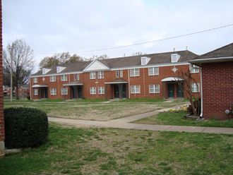 a row of brick apartment buildings on a grass yard