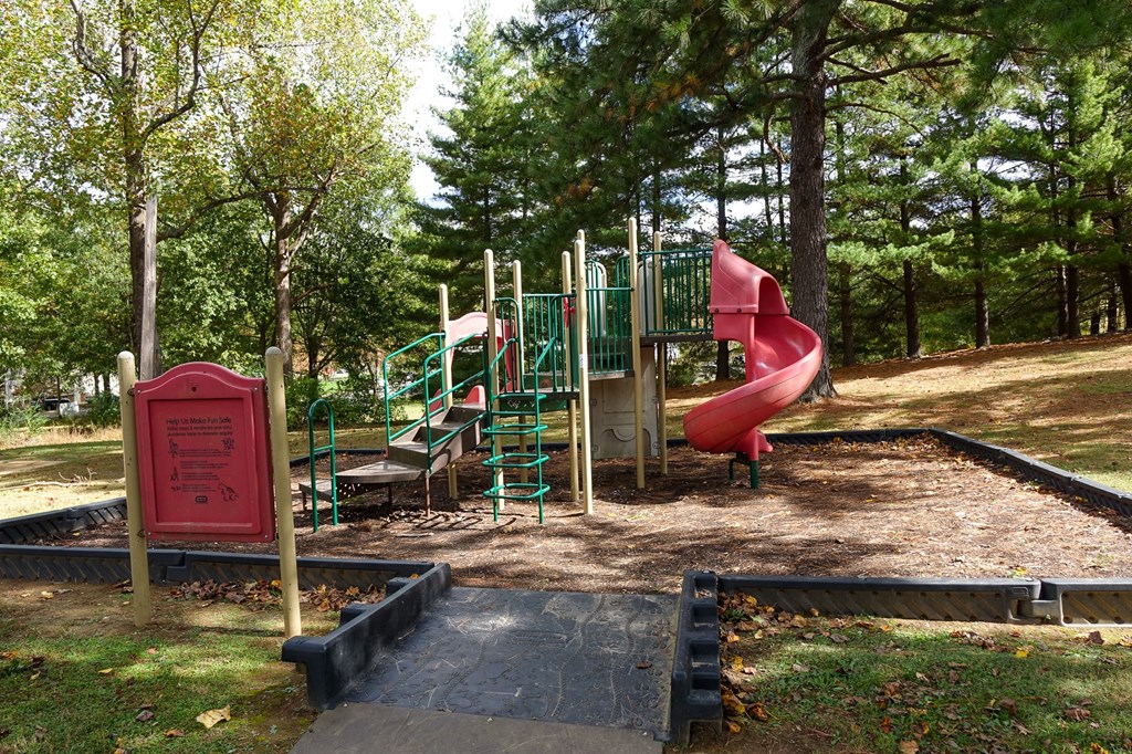 a playground with a red slide in a park
