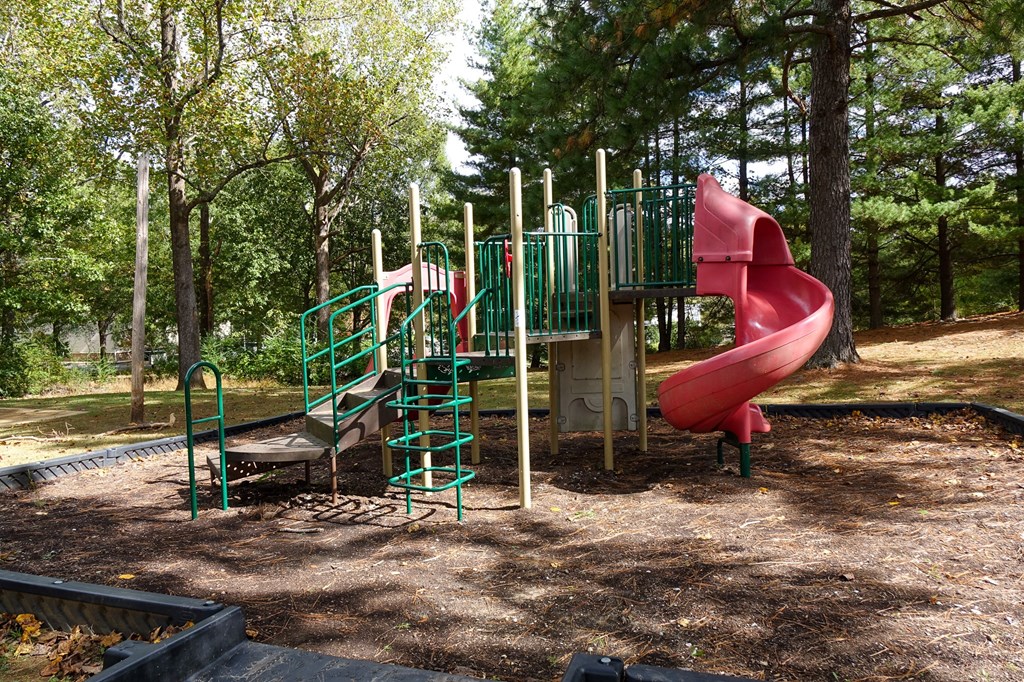 a playground with a pink slide and a green climbing structure