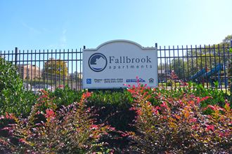 a picture of the fallbrook apartments sign with colorful flowers in the foreground