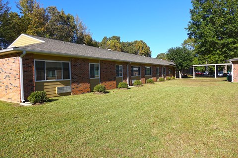 a view of the exterior of a brick building with a large grassy area in front of