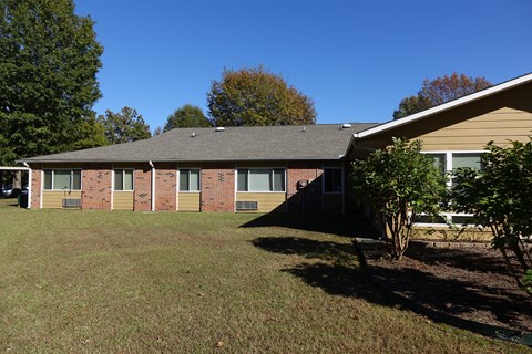 A building with a brown roof and a green lawn in front.
