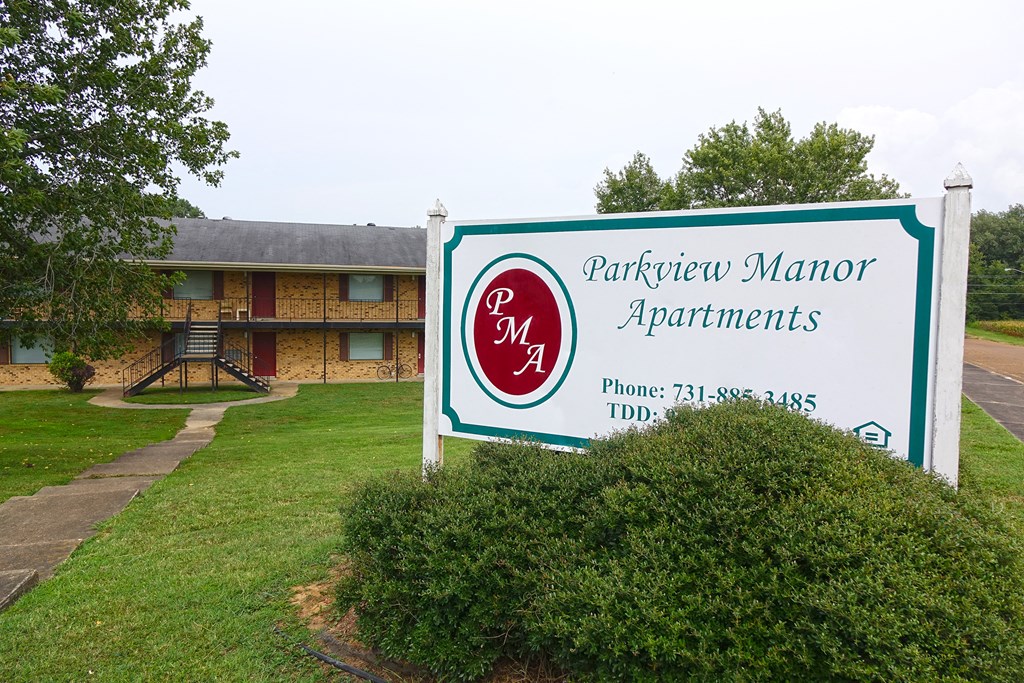 a sign for the partnership manor apartments in front of a building