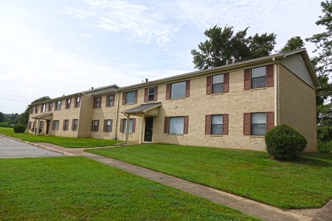 an apartment building with a green lawn and a sidewalk