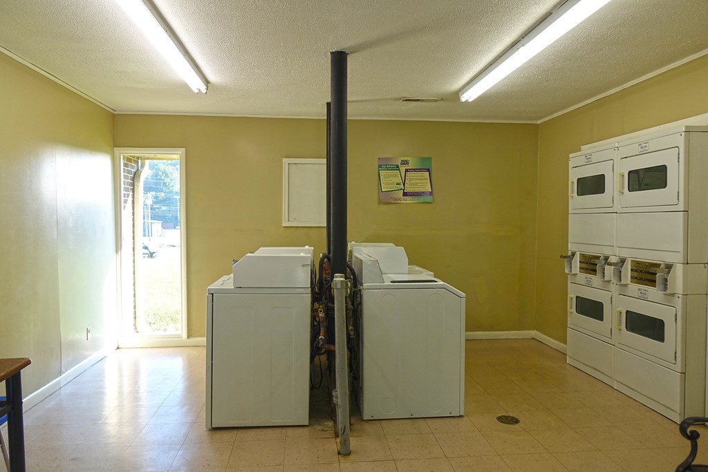 a laundry room with yellow walls and white washers and dryers