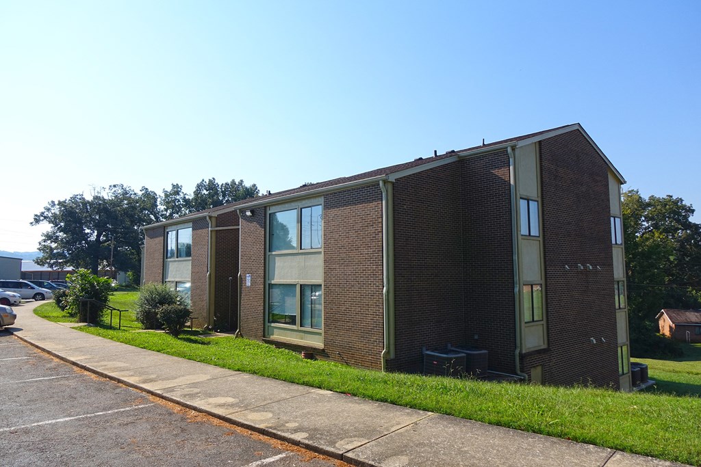 a brick building with green grass and a blue sky in the background