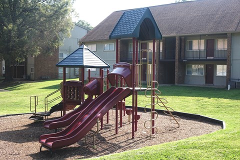 A playground with a red slide and a red and black play structure.