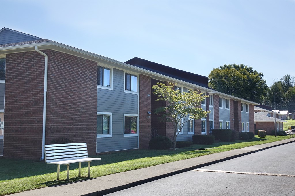 a bench in front of a brick apartment building