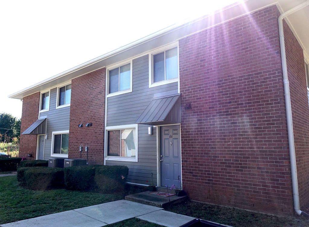 the side of a brick house with a sidewalk in front of it
