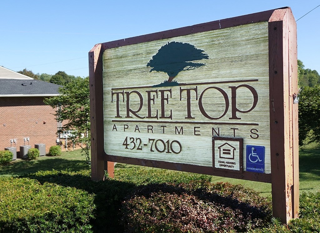 a sign for tree top apartments in front of a building