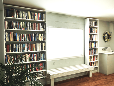a book shelf with a window and a bench
