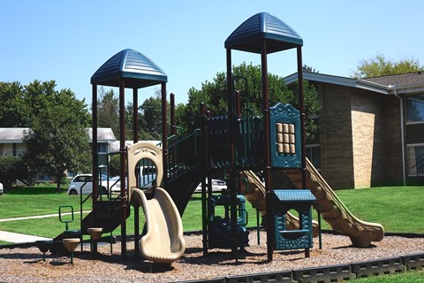 a playground with a playset and slides in front of a building