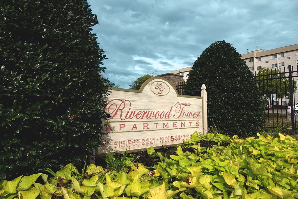 a sign in front of a building with trees and bushes