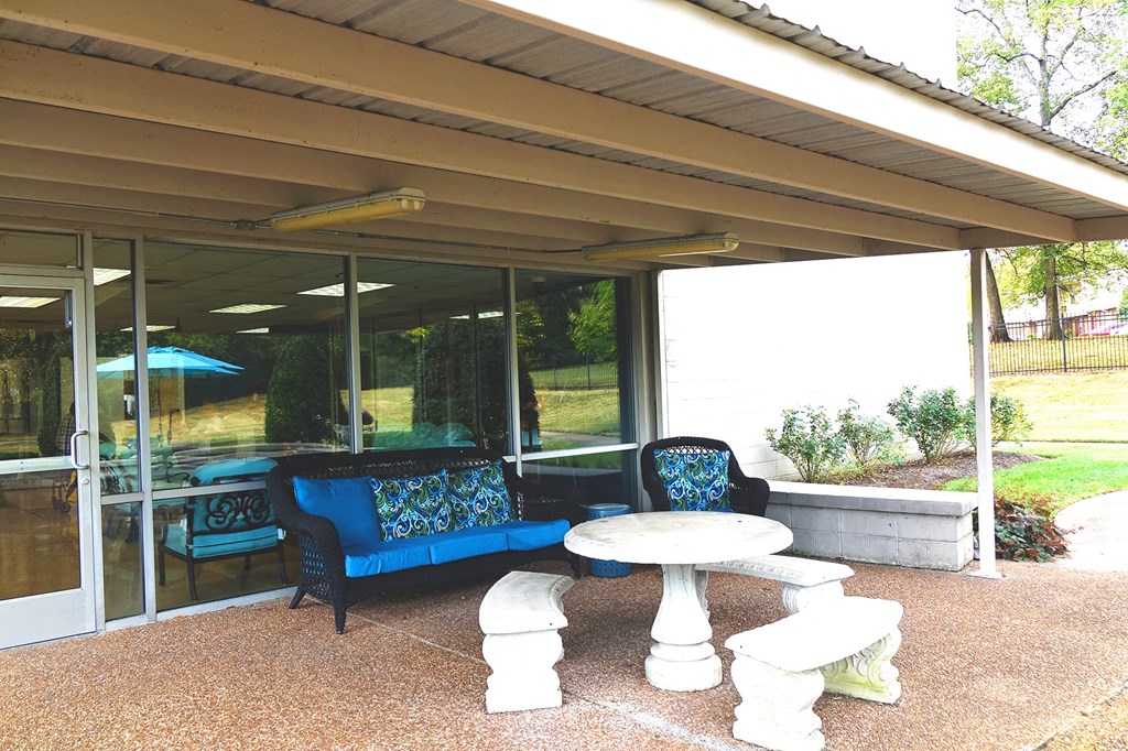 a covered patio with blue chairs and a white table
