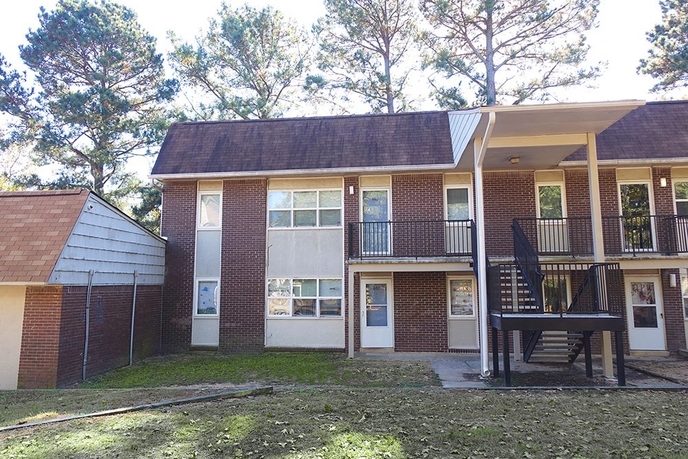 the front of a brick house with a porch and a staircase