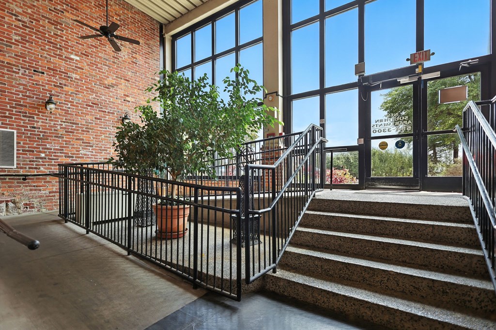 A potted plant sits on a patio next to a staircase.