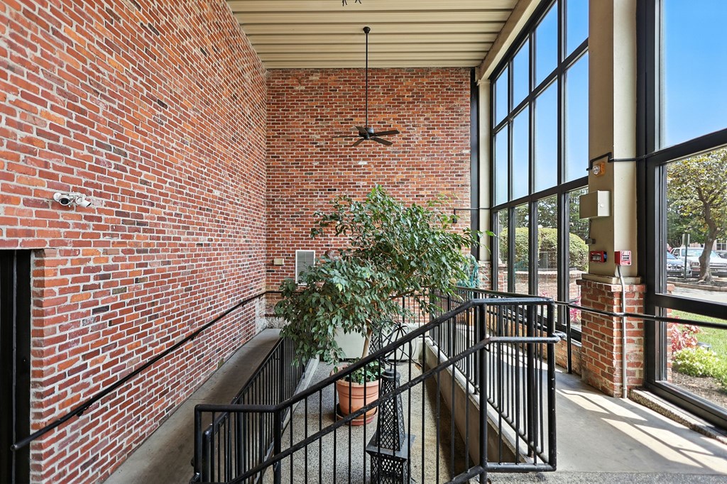 A potted plant sits on a balcony with a brick wall.