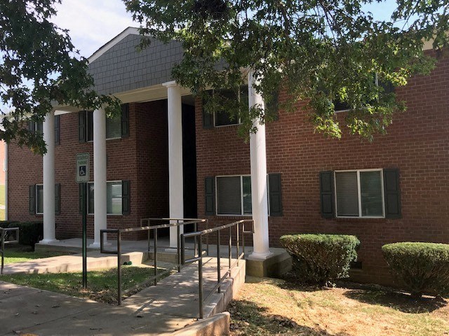 a brick building with three pillars and a sidewalk