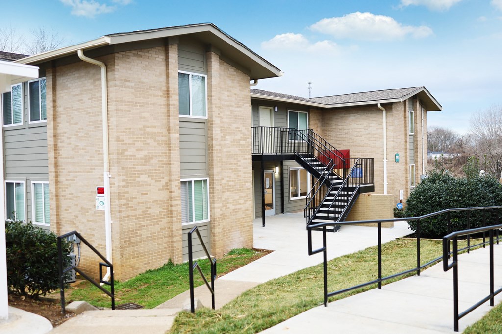 an apartment building with stairs and a sidewalk