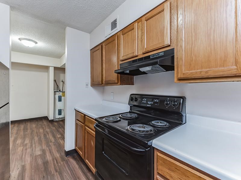 A kitchen with a black stove top oven and wooden cabinets.