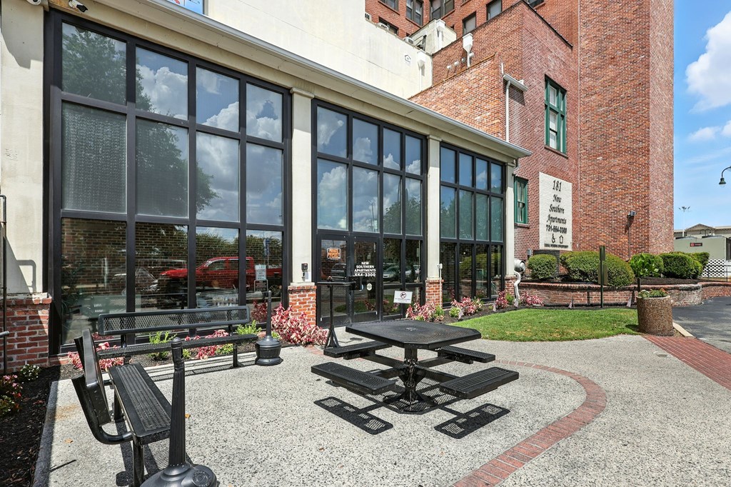 A black picnic table is in front of a building with a brick facade.