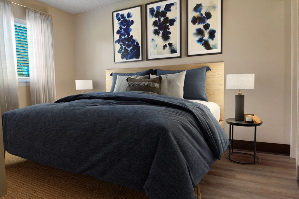 A bedroom with a large bed and two blue abstract paintings on the wall.