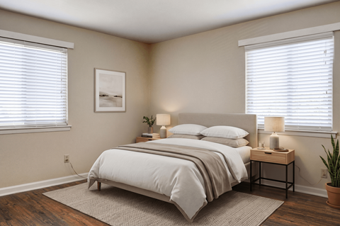A bedroom with a large bed and a small table with a lamp on it.