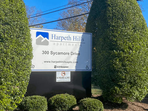 A sign for Harpeth Hills Apartments is surrounded by green bushes.
