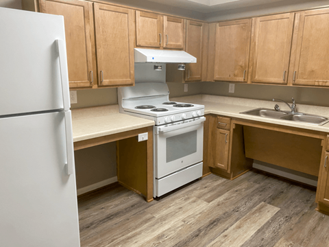 A kitchen with a white fridge, white stove, and wooden cabinets.