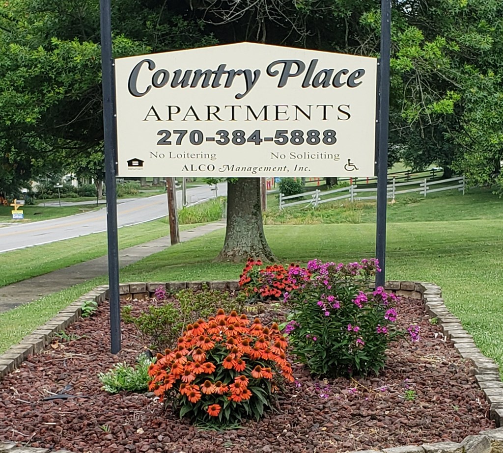 a sign for country place apartments in front of a garden