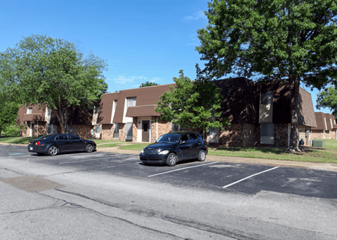 Two cars parked in a parking lot in front of a building.
