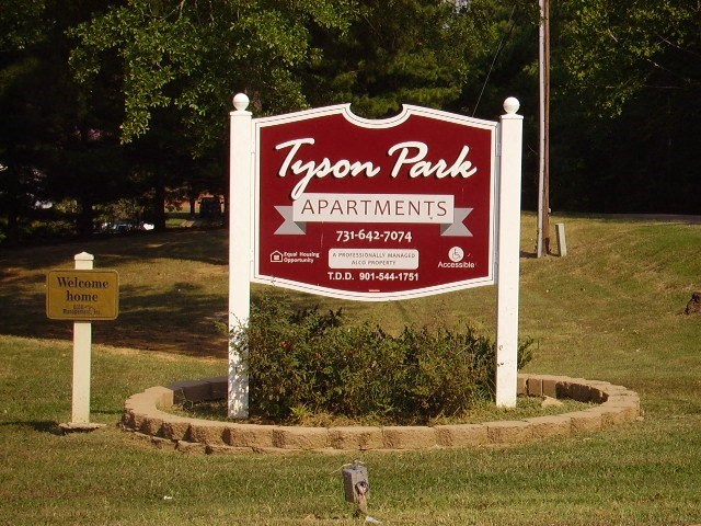 a sign for tyson park apartments in the grass