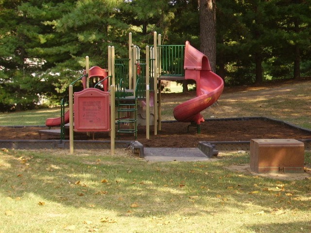 a playground with a red slide in a park
