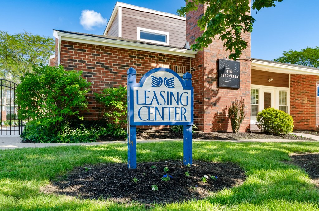 A blue sign that says Leasing Center in front of a brick building.