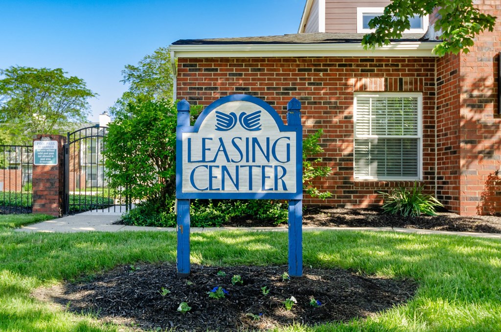 A blue sign that says Leasing Center in front of a brick building.