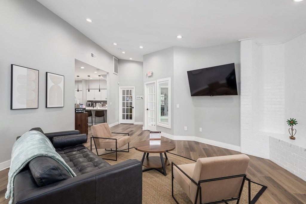 A living room with a black couch and a television on the wall.