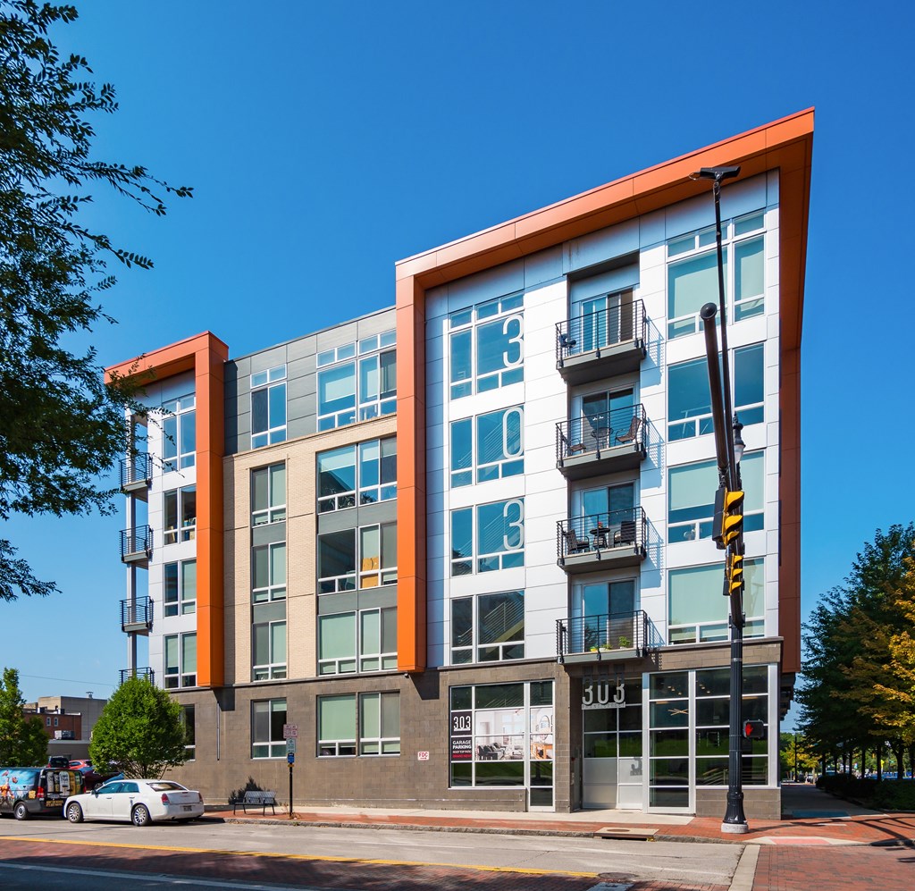 A modern building with orange and white accents stands on a street corner.