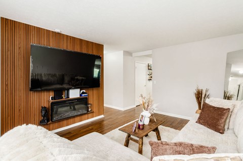 A living room with a white couch and a wooden wall.