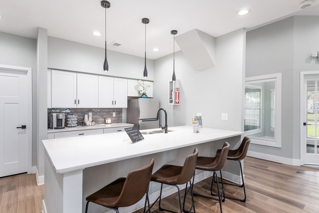 A kitchen with white countertops and brown chairs.
