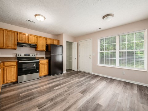 A kitchen with wooden cabinets and a black refrigerator.