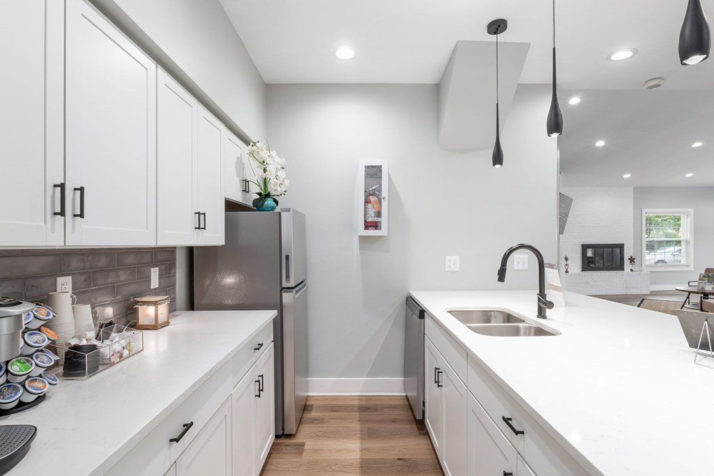 A kitchen with white cabinets and a grey backsplash.