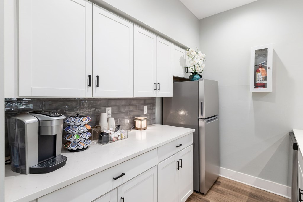 A kitchen with white cabinets and a stainless steel refrigerator.