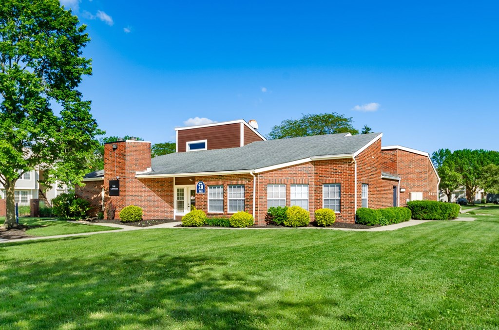 A red brick building with a green lawn in front.