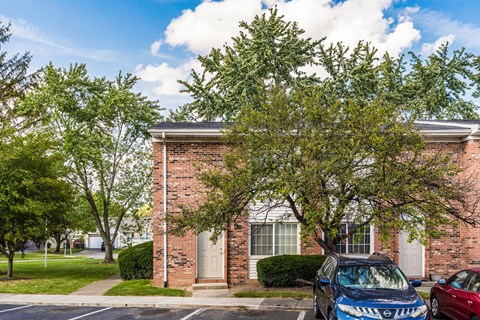 Brick townhome exterior with parking and mature trees at Northtowne Apartments, Columbus, 43229