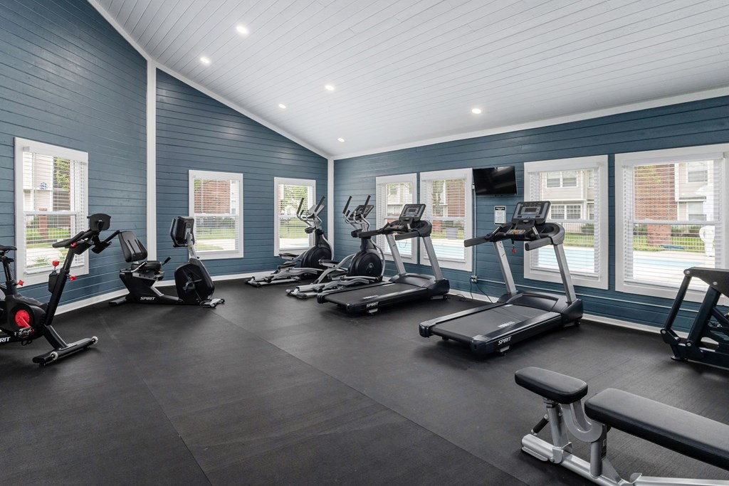 A spacious gym with treadmills, exercise bikes, and a bench.
