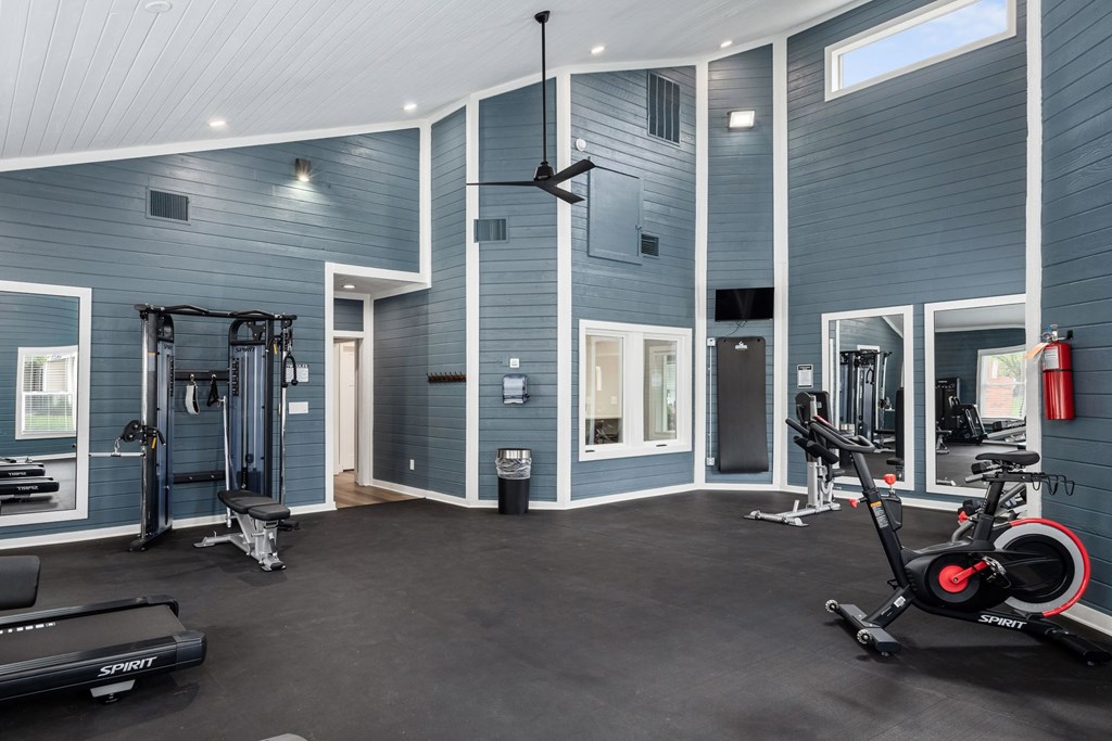 A gym with a variety of equipment including a treadmill, a stationary bike, and a weight bench.