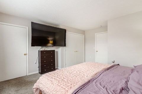 A bedroom with a bed, dresser, and television.
