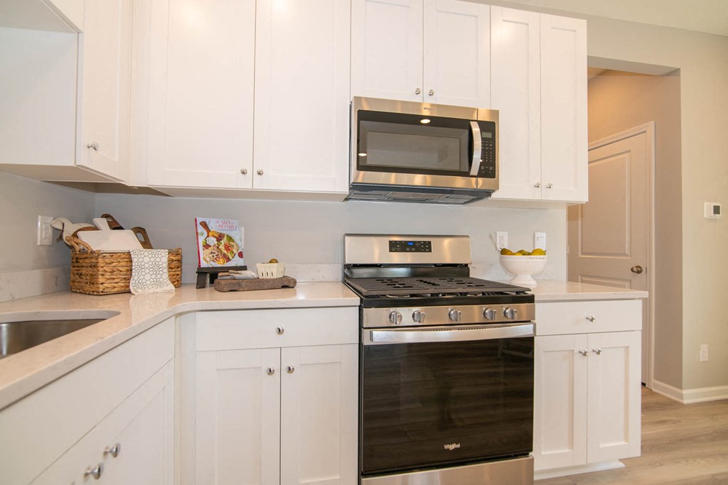 a white kitchen with black appliances and white cabinets at Jackson Run Townhomes, Whitestown, 46075