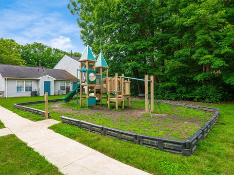 A playground with a green slide and a wooden structure.