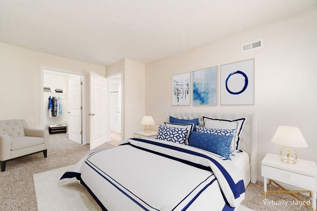 A bedroom with a large bed and a chair.